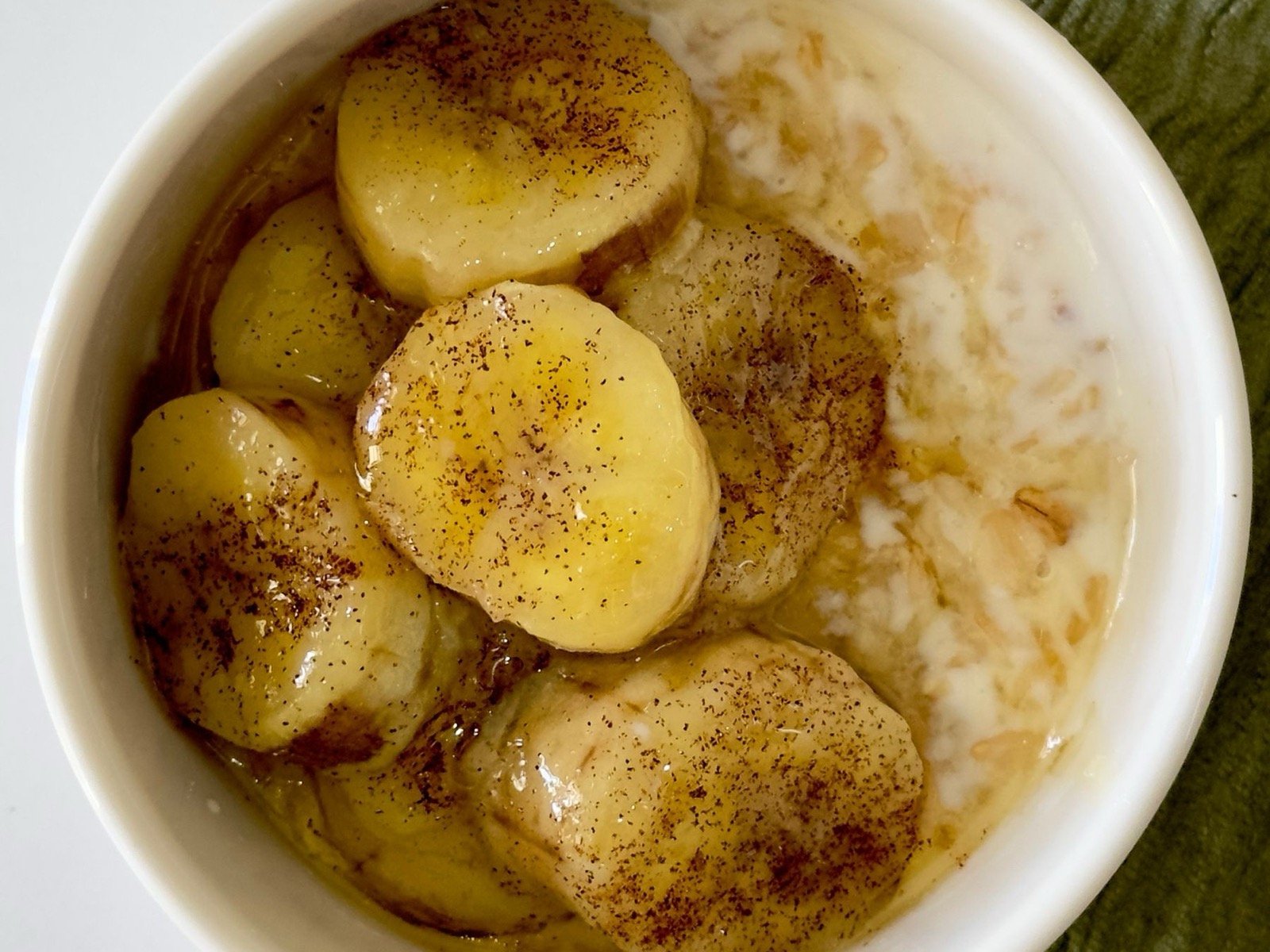 Ciotola bianca con crema di avena e yogurt greco, banana morbida a fette e cannella, colazione della fase semiliquida, chirurgia maxillo-facciale a Caserta e Napoli