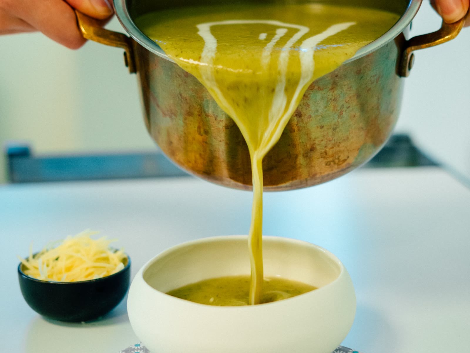 Crema di zucchine versata dalla pentola in una ciotola con il parmigiano accanto, fase semiliquida del recupero, chirurgia maxillo-facciale a Caserta e Napoli
